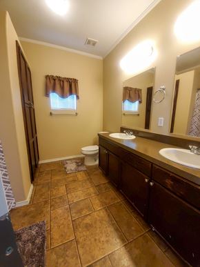 Walsenburg house for rent - A bathroom with a toilet, sink, and brown tiles.