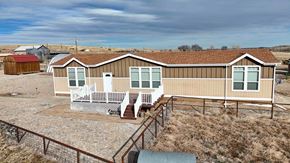 Walsenburg house for rent - A house with a brown roof and a porch with white chairs.