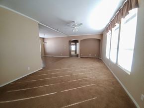 Walsenburg house for rent - A spacious room with a carpeted floor and a ceiling fan.