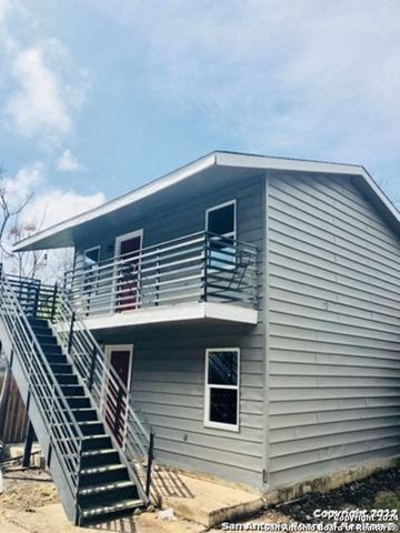 San Antonio apartment for rent - A house with a grey siding and a staircase leading to the second floor.