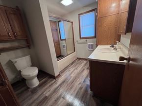 Wapakoneta house for rent - A bathroom with a toilet, sink, and wooden cabinets.