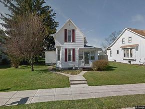 Wapakoneta house for rent - A white house with a red door and a tree in front.