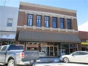 Grinnell apartment for rent - A silver truck is parked in front of a building with a brown awning.
