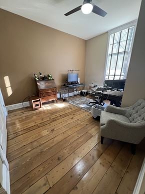 Grinnell apartment for rent - A room with wooden floors and a ceiling fan.