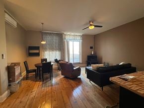 Grinnell apartment for rent - A living room with a black couch, a wooden table, and a window with curtains.