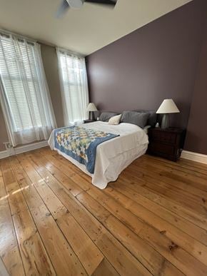 Grinnell apartment for rent - A bedroom with a bed, two lamps, and a window with white curtains.