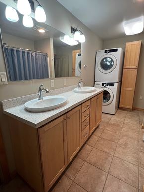 Grinnell apartment for rent - A bathroom with a double sink and a washer and dryer.