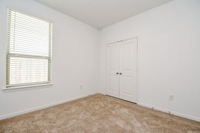 Katy house for rent - A room with a carpeted floor, a window with blinds, and a white door.