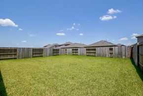 Katy house for rent - A large grassy field with a wooden fence and houses in the background.