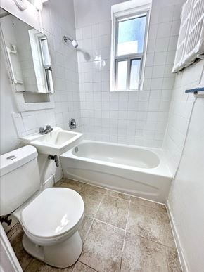 Toronto apartment for rent - A white toilet sits in a small bathroom with a white tub and sink.