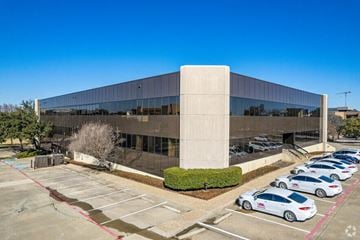 Irving apartment for rent - A parking lot with cars and a modern building.