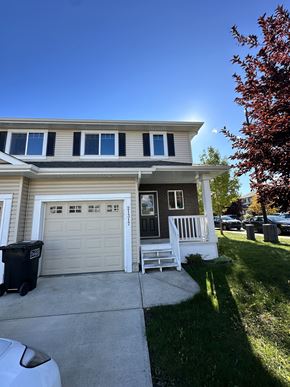 Edmonton apartment for rent - A house with a white garage door and a black trash bin in front of it.