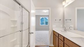 Hastings house for rent - A bathroom with a glass shower door and a view of a blue building outside the window.