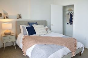 Philadelphia apartment for rent - A bedroom with a bed covered in a pink blanket and a white nightstand with a lamp.