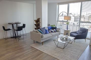 Philadelphia apartment for rent - A living room with a grey couch, a black chair, a glass table and a wooden floor.