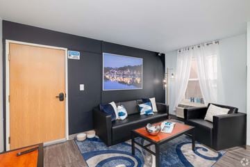 Philadelphia apartment for rent - A living room with a couch, chair, and a television playing a show.