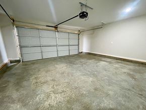 Louisville house for rent - A spacious garage with a closed white door and a concrete floor.