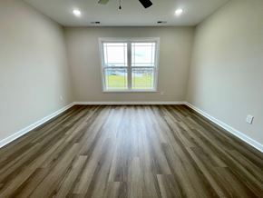 Louisville house for rent - A room with wooden flooring and a window overlooking a grassy field.