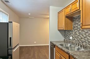 Forest Park apartment for rent - A kitchen with a refrigerator, wooden cabinets, and a tiled backsplash.
