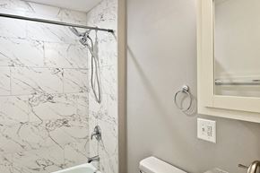 Forest Park apartment for rent - A white bathroom with a marble tile shower.