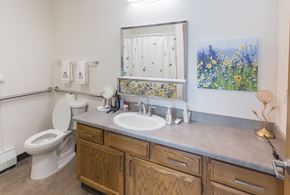 Longmont apartment for rent - A bathroom with a toilet, sink, and a painting of flowers on the wall.