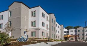 Longmont apartment for rent - A large white building with a blue and white peacock statue in front.