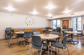 Longmont apartment for rent - A room with tables and chairs and a clock on the wall.