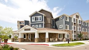 Longmont apartment for rent - A large, modern building with a stone foundation and a covered walkway.