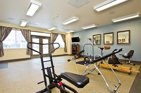Longmont apartment for rent - A gym room with a rowing machine, a bench, and mirrors on the wall.