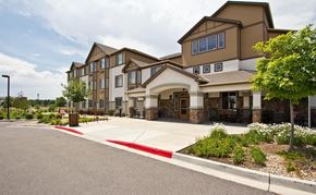 Longmont apartment for rent - A large building with a parking lot in front.