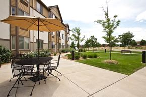 Longmont apartment for rent - A patio with a table and chairs and a yellow umbrella.