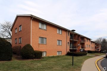 Hagerstown apartment for rent - A red brick apartment building with a sidewalk and green bushes.