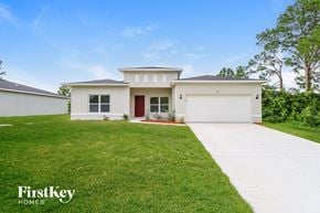 Palm Bay house for rent - A white house with a red door is for sale by FirstKey Homes.