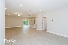 Palm Bay house for rent - A spacious room with light wood flooring and white walls, with a door on the right and a window on the left.