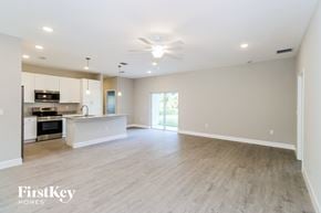 Palm Bay house for rent - A spacious living room with a kitchen in the background and a sliding glass door leading to a balcony.