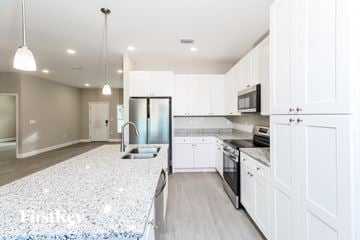 Palm Bay house for rent - A modern kitchen with white cabinets and a granite countertop.