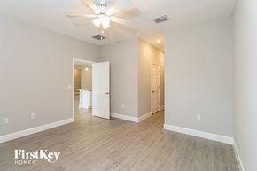 Palm Bay house for rent - A spacious room with a ceiling fan and light fixture, and a doorway leading to another room.