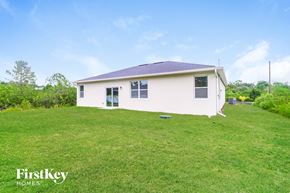 Palm Bay house for rent - A white house with a blue roof is surrounded by green grass.