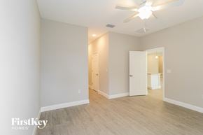 Palm Bay house for rent - A spacious room with a ceiling fan and light fixture, and a doorway leading to another room.