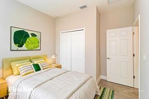 Palm Bay house for rent - A bedroom with a white bed and a painting of green leaves on the wall.