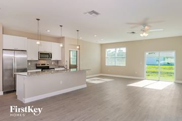 Palm Bay house for rent - A spacious kitchen with a refrigerator, microwave, and a countertop with a sink.