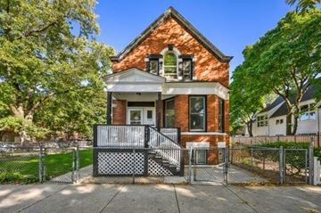 Chicago apartment for rent - A red brick house with a black and white fence in front.