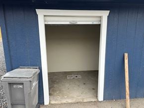 Kennewick house for rent - A blue building with a white door and a grey dumpster with the number 0171242 on it.