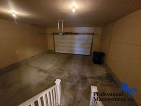 Billings house for rent - A spacious garage with a white railing and a black trash bin.