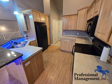 Billings house for rent - A kitchen with wooden cabinets and a black fridge.