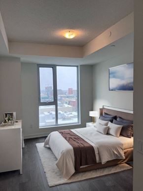 Kitchener house for rent - A bedroom with a large bed and a view of the city.