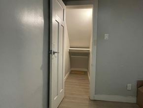 Hamilton apartment for rent - A white door is open to a hallway with wood flooring.