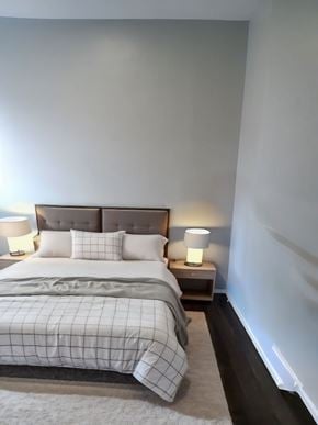 Hamilton apartment for rent - A bed with a white comforter and two lamps on bedside tables.