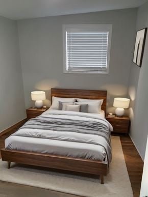 Hamilton apartment for rent - A bed with a grey comforter and two white pillows is in the center of a room with a white rug and two lamps on either side of the bed.