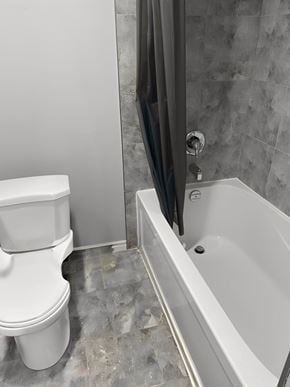 Hamilton apartment for rent - A white toilet sits next to a bathtub in a bathroom.